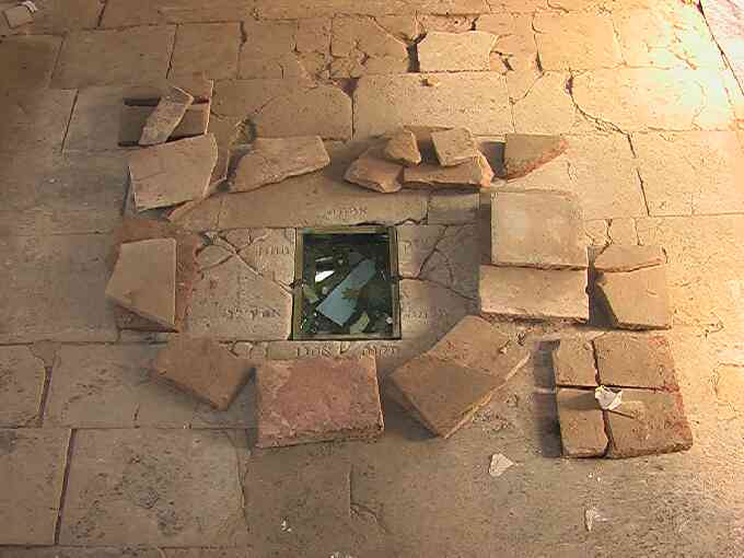 Steinfußboden mit zerbrochenen Steinplatten mit einem eingelassenen Kunstwerk