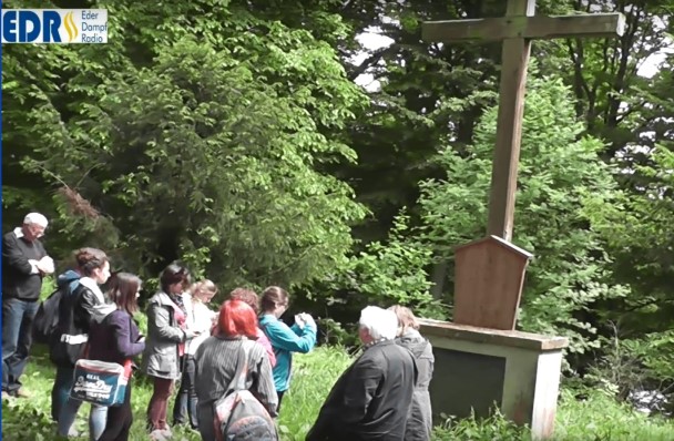 Video Still einer Menschengruppe vor einem Kreuz