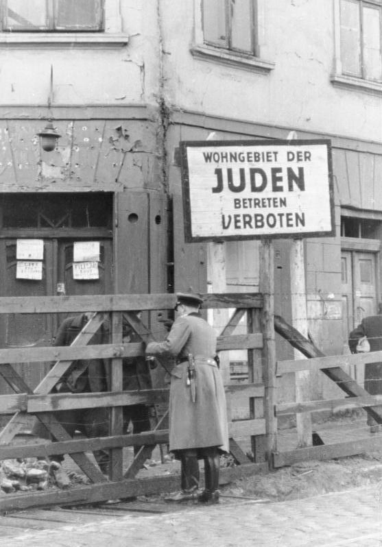 Wachtposten an Tor, dahinter Schild „Wohngebiet der Juden. Betreten verboten“