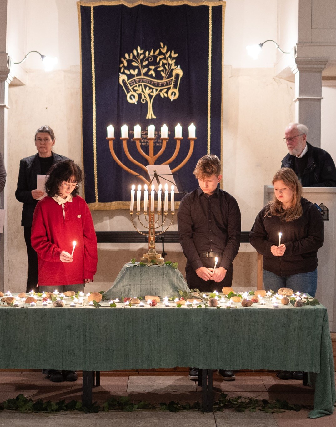 5 Personen in Synagoge vor Kerzenmeer